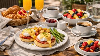 A leisurely weekend brunch table with eggs Benedict, fresh pastries, mimosas, fresh fruit, and coffee, set on a sunlit patio with linen napkins