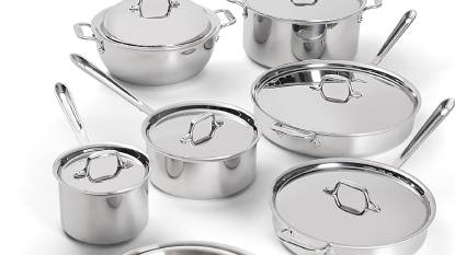 The All-Clad D3 14-Piece Stainless Steel Cookware Set arranged on a kitchen counter, showing the polished exteriors and riveted handles